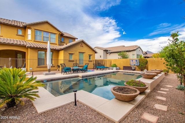 back of property featuring a fenced in pool, fence, a tiled roof, stucco siding, and a patio area