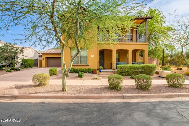 view of front of house featuring covered porch, stucco siding, driveway, a balcony, and an attached garage