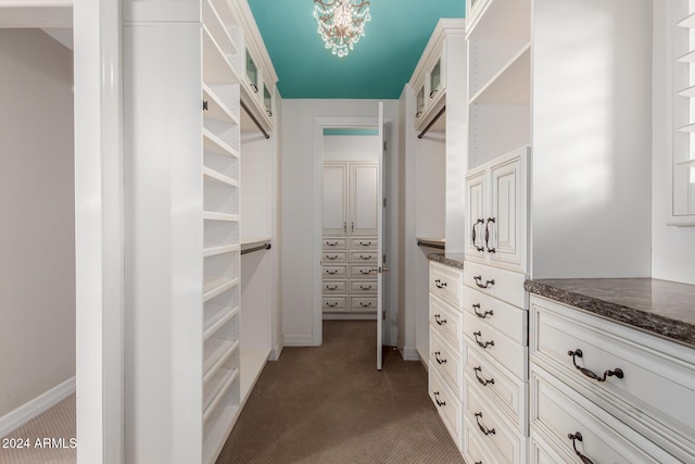 spacious closet with light colored carpet and a chandelier