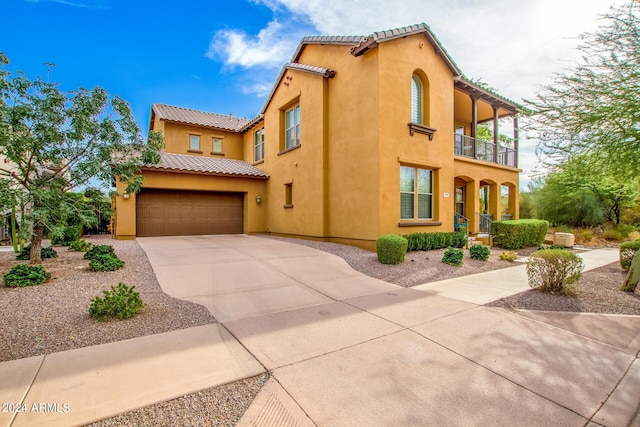 mediterranean / spanish-style home featuring a garage, stucco siding, and a balcony