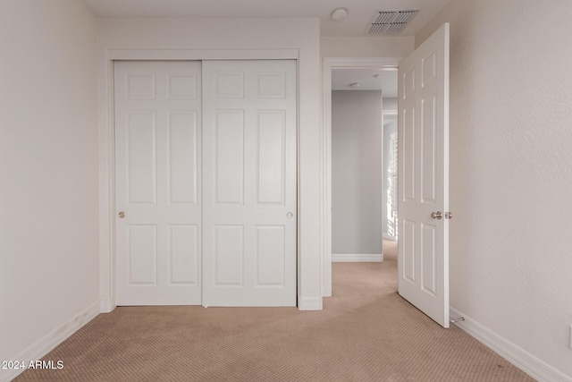 unfurnished bedroom with light colored carpet and a closet