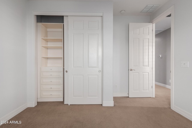 unfurnished bedroom with a closet, visible vents, light colored carpet, and baseboards