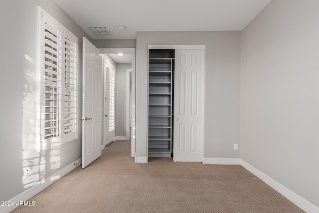 unfurnished bedroom featuring light colored carpet and a closet