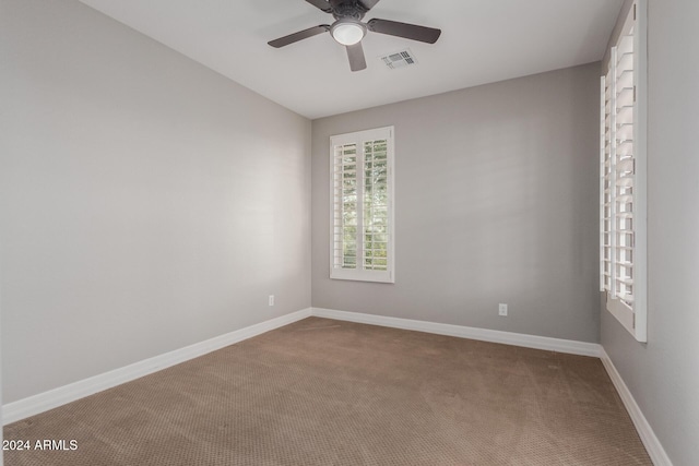 carpeted spare room with ceiling fan and baseboards