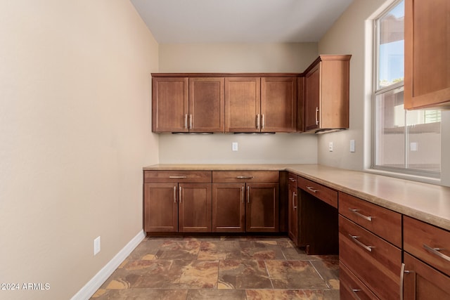 kitchen with stone finish floor, light countertops, and baseboards