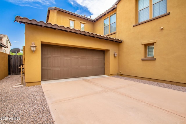 view of front of home featuring a garage, fence, driveway, and stucco siding