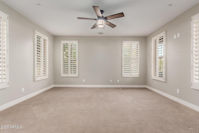 empty room with ceiling fan, baseboards, and carpet