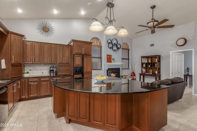 kitchen with paneled fridge, dishwashing machine, a kitchen island, brown cabinets, and a glass covered fireplace