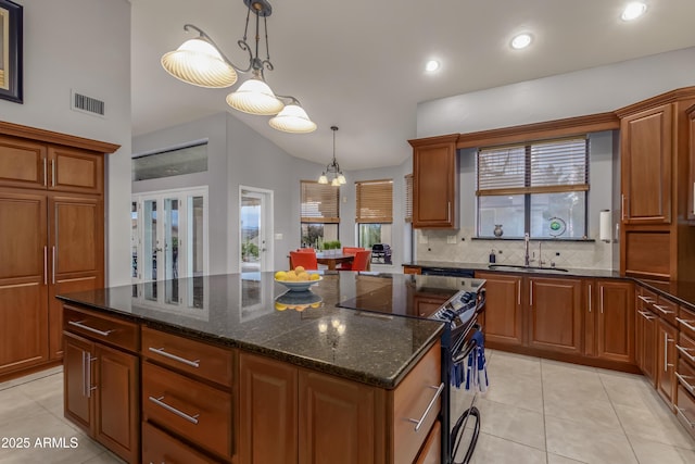 kitchen with electric range, a kitchen island, a sink, visible vents, and tasteful backsplash