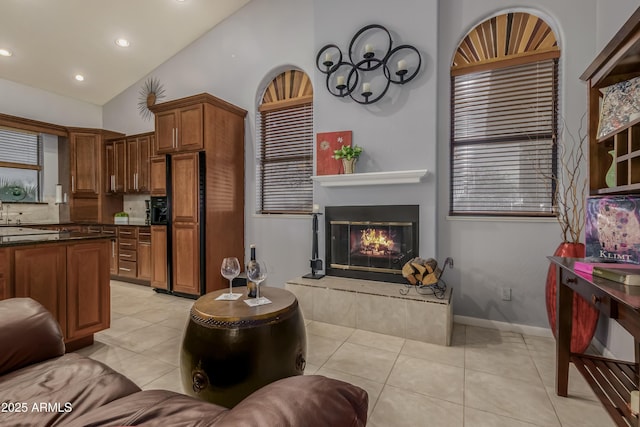 kitchen featuring light tile patterned floors, dark countertops, paneled built in fridge, brown cabinetry, and a glass covered fireplace