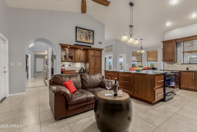 living room featuring arched walkways, light tile patterned floors, visible vents, high vaulted ceiling, and baseboards