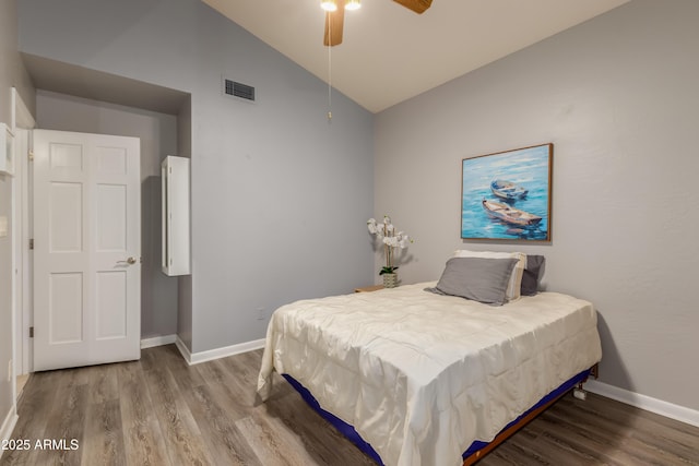 bedroom with lofted ceiling, wood finished floors, visible vents, and baseboards