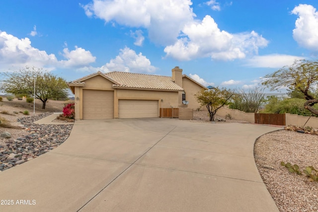 view of front of property with an attached garage, a tiled roof, driveway, stucco siding, and a chimney