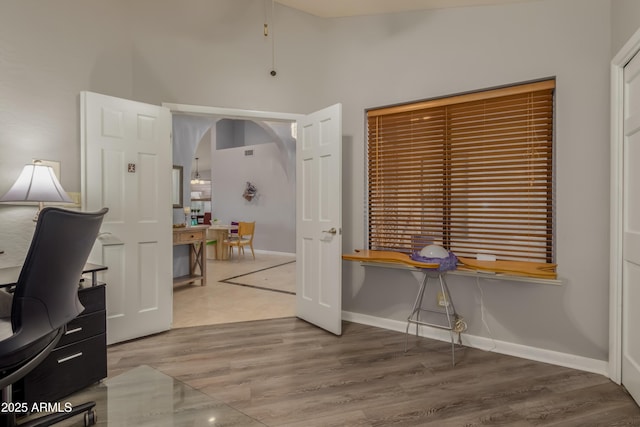 office featuring lofted ceiling, baseboards, and wood finished floors