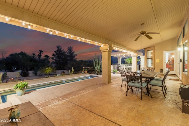 patio terrace at dusk featuring ceiling fan, outdoor dining space, fence, and a fenced in pool