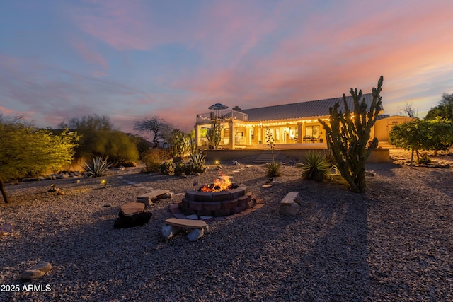 back of house at dusk with a fire pit