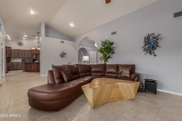 living area featuring arched walkways, light tile patterned flooring, visible vents, and baseboards