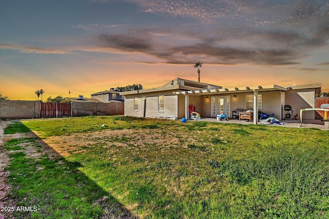 exterior space featuring a fenced backyard, a patio, brick siding, and a lawn