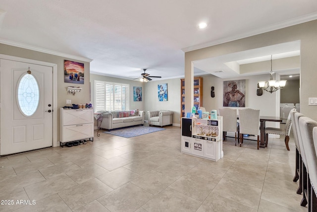 living room with ceiling fan with notable chandelier, ornamental molding, light tile patterned floors, and washing machine and dryer