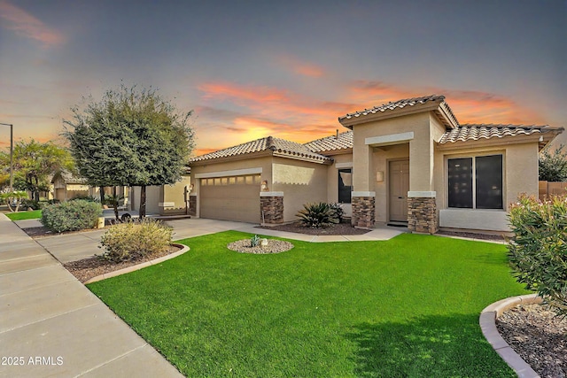 mediterranean / spanish-style home featuring a garage, concrete driveway, stone siding, stucco siding, and a front lawn