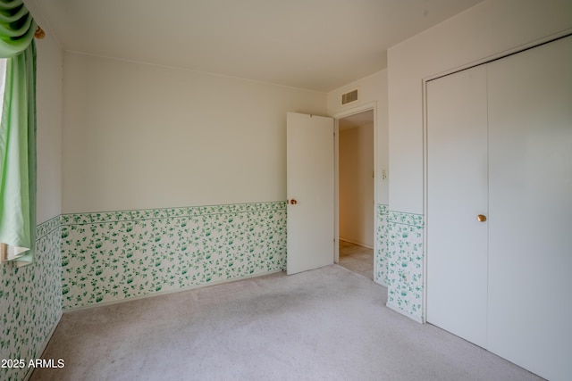 interior space featuring visible vents, carpet, and a wainscoted wall