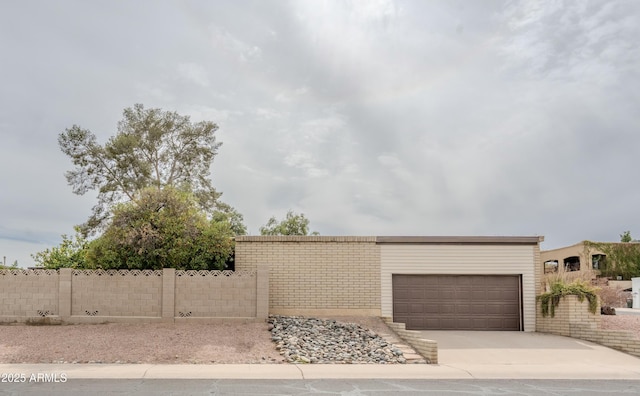 view of front of home with concrete driveway and fence