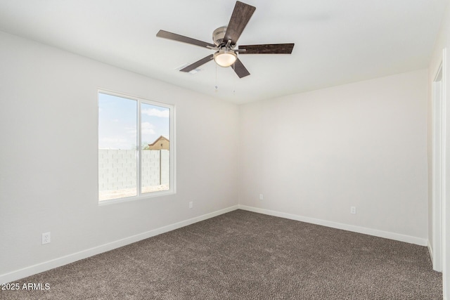 spare room featuring baseboards, dark carpet, and ceiling fan