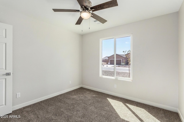 spare room featuring a ceiling fan, dark colored carpet, visible vents, and baseboards