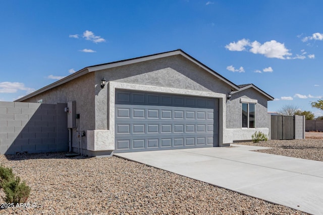 view of side of property with concrete driveway, an attached garage, fence, and stucco siding