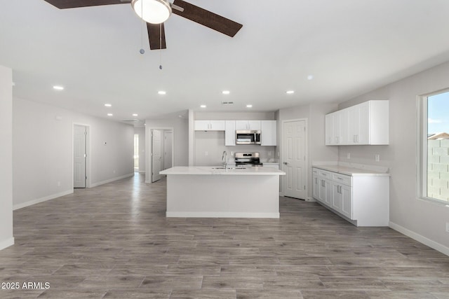 kitchen with white cabinets, appliances with stainless steel finishes, open floor plan, a sink, and recessed lighting