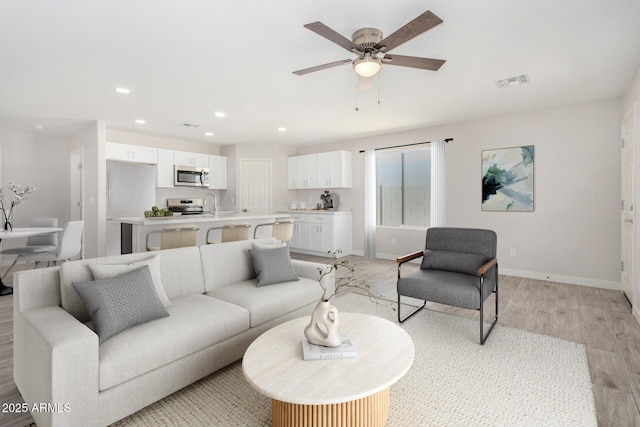 living room featuring recessed lighting, visible vents, a ceiling fan, light wood-type flooring, and baseboards