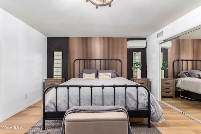 bedroom featuring a wall mounted AC, a closet, and light hardwood / wood-style floors