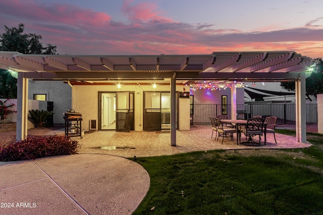 back house at dusk with a lawn, a pergola, and a patio