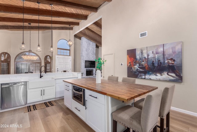 kitchen featuring white cabinetry, stainless steel appliances, wood counters, high vaulted ceiling, and decorative light fixtures