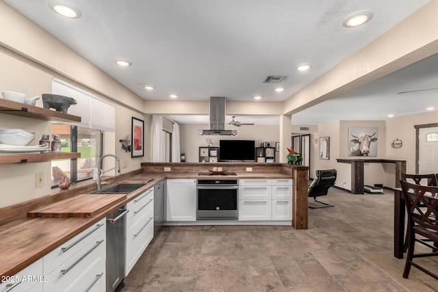 kitchen with island range hood, visible vents, butcher block countertops, oven, and a sink