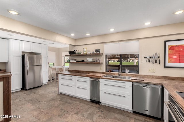 kitchen with appliances with stainless steel finishes, plenty of natural light, a sink, and white cabinets