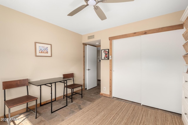 home office featuring a ceiling fan, stone finish floor, visible vents, and baseboards