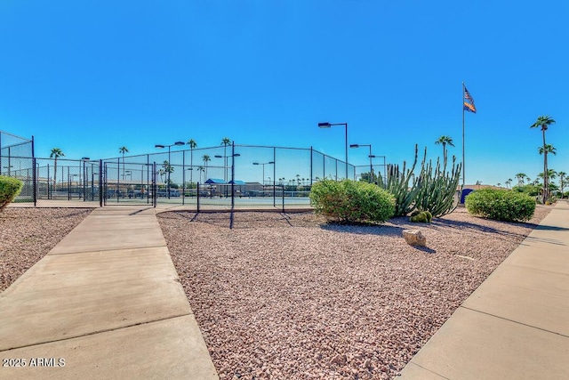 view of home's community featuring a tennis court and fence