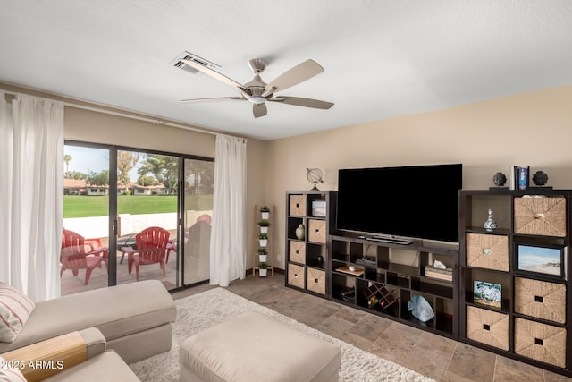 living area featuring a ceiling fan, stone finish floor, and visible vents