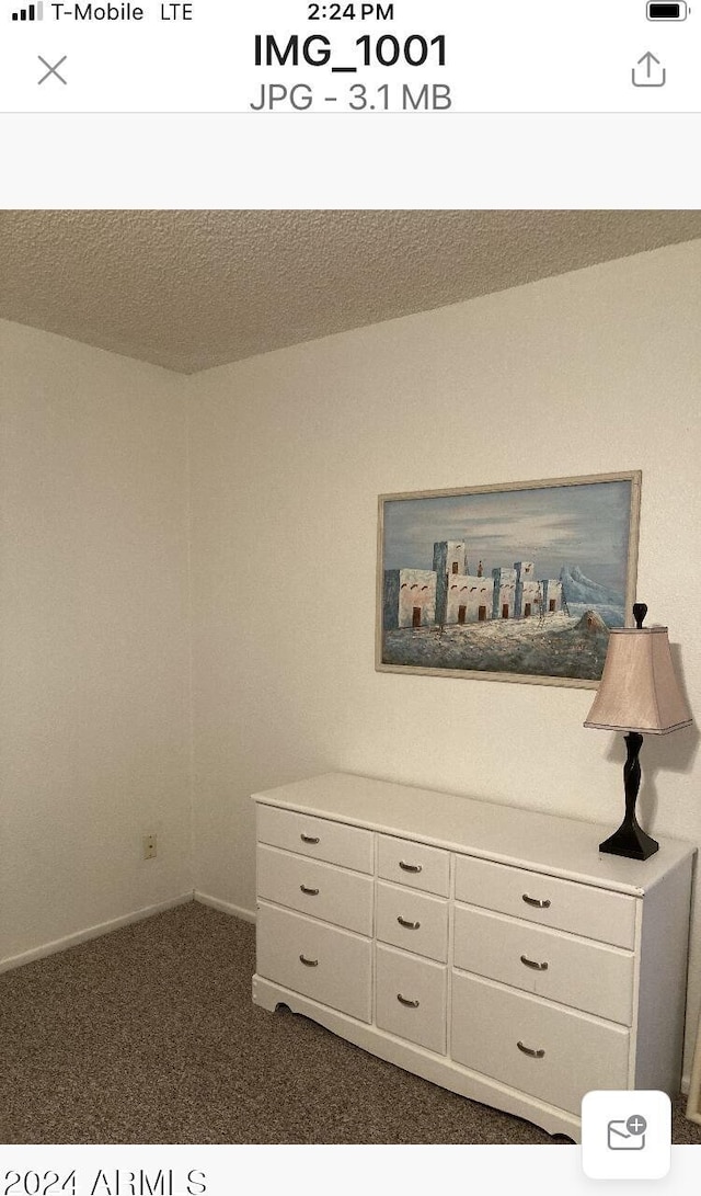 interior space featuring a textured ceiling and dark carpet