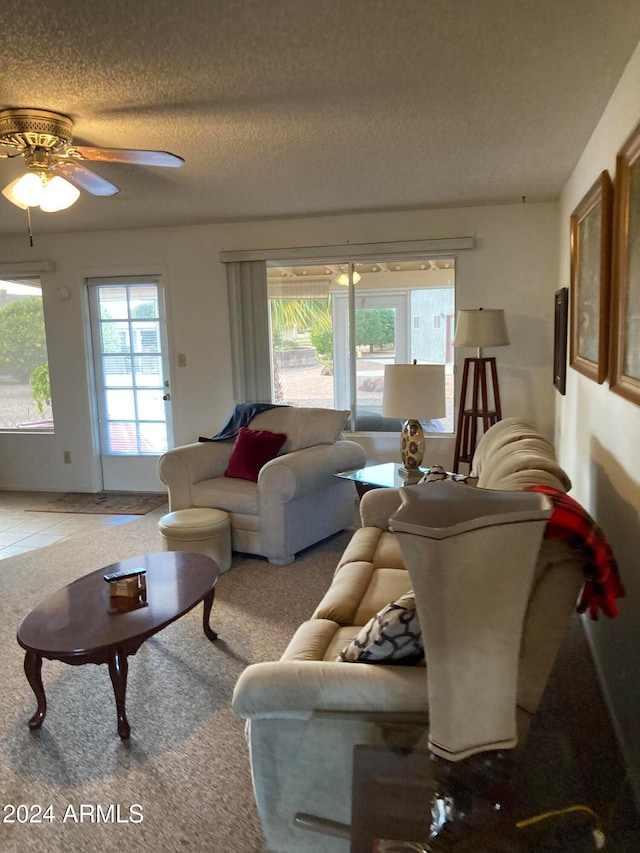 living room featuring ceiling fan, a healthy amount of sunlight, a textured ceiling, and carpet flooring