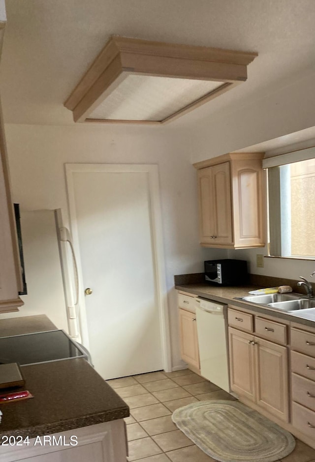 kitchen featuring white dishwasher, sink, light brown cabinetry, and light tile patterned floors