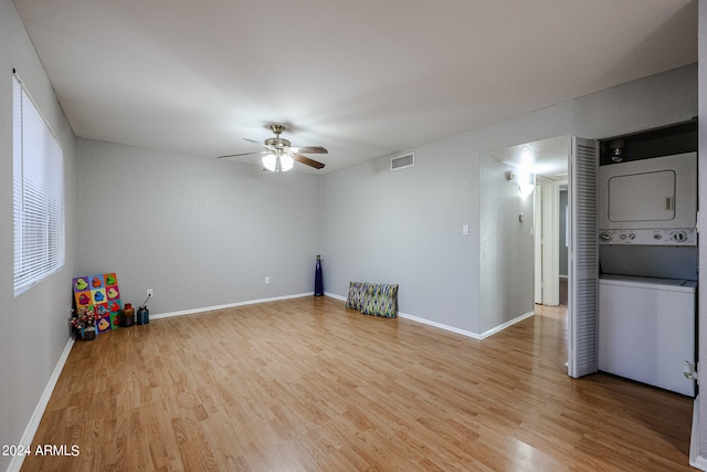 interior space featuring light wood-type flooring, ceiling fan, and stacked washer / drying machine