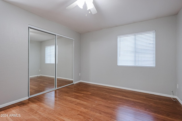 unfurnished bedroom with multiple windows, hardwood / wood-style floors, ceiling fan, and a closet