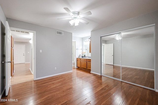 unfurnished bedroom featuring wood-type flooring, sink, ceiling fan, and a closet