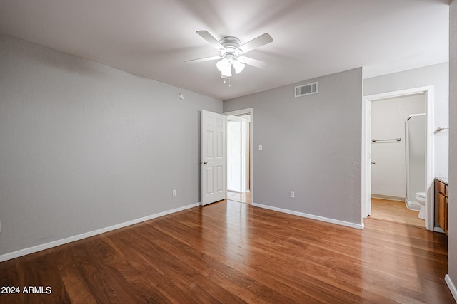 unfurnished bedroom featuring wood-type flooring, ensuite bath, and ceiling fan