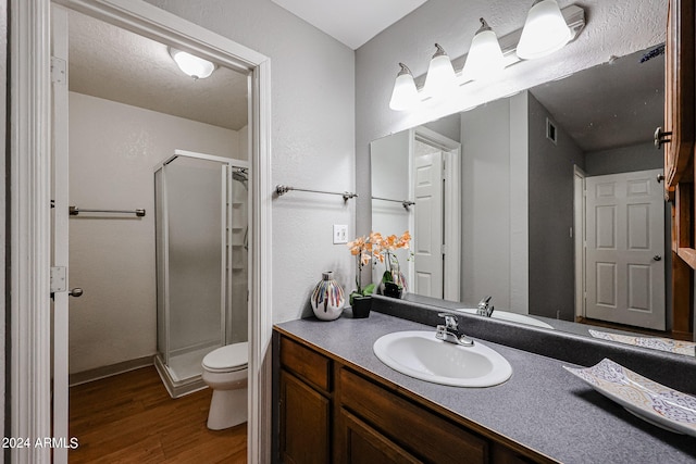 bathroom with wood-type flooring, vanity, a shower with shower door, and toilet