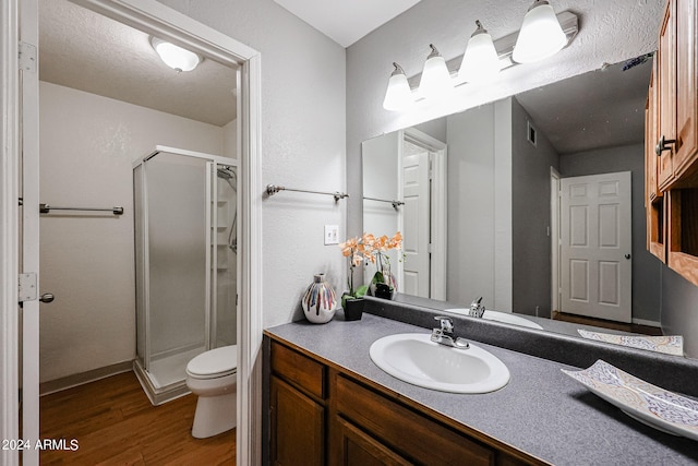 bathroom featuring vanity, wood-type flooring, an enclosed shower, and toilet