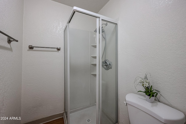 bathroom featuring toilet and a shower with door