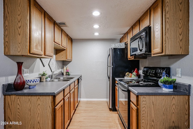 kitchen featuring light hardwood / wood-style flooring, black appliances, a textured ceiling, and sink